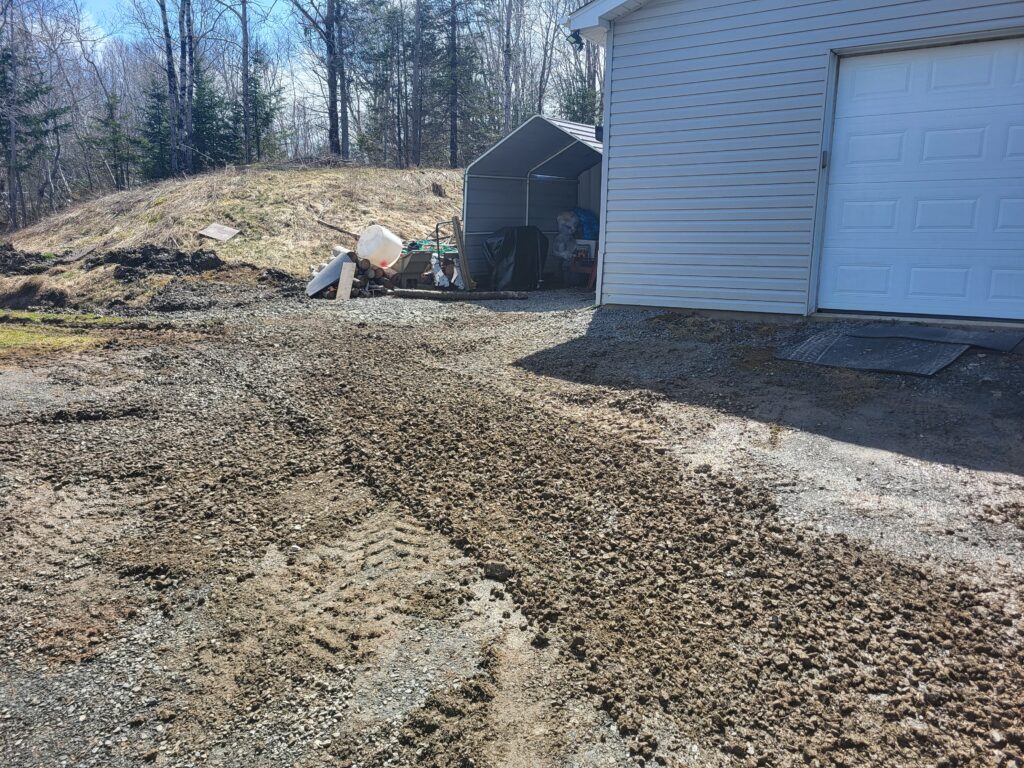 Residential driveway site prep and grading work in progress beside a garage in the Halifax area, showing early-stage excavation by FTF Excavation